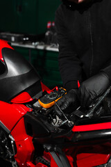 Digital multimeter reads motorcycle battery voltage during inspection. Mechanic testing battery...