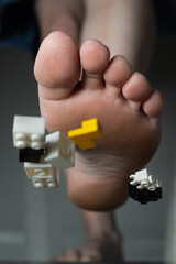 A bare foot is surrounded by colorful construction toy bricks, illustrating a playful moment at...