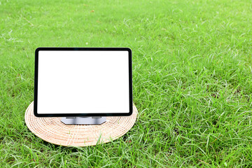 A tablet mockup with a large blank display, placed on a lush grassy meadow under a bright blue sky