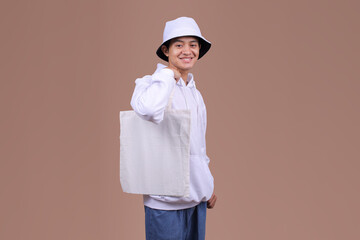 Male Model with Cotton Tote Bag on Neutral Background for Mockup and Eco-Friendly Concept