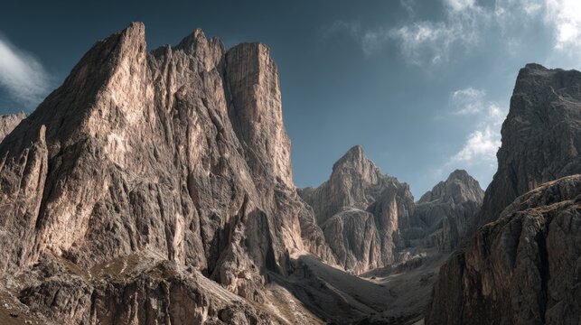 Dramatic mountain landscape with steep rocky cliffs and rugged terrain under cloudy sky.