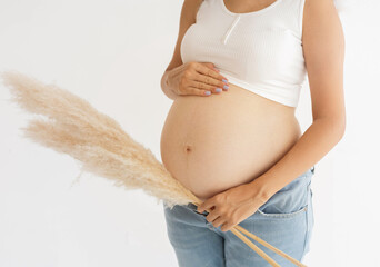 Pregnant Woman in White Crop Top and Jeans Holding Pampas Grass
