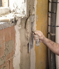 Craftsman uses a float trowel and cement to plaster a house wall. Construction process
