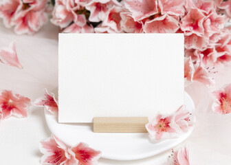 Blank horizontal paper card near pink azalea flowers closeup, spring wedding mockup