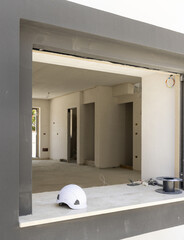 White hard Safety helmet on the window sill in a new house construction site. Protection equipment