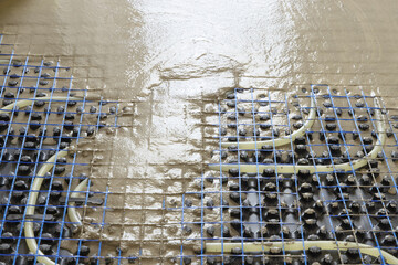 Liquid concrete is poured over floor heating installation in a new building. Modern construction system