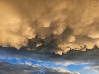 Storm clouds on sunset. Light in the dark and dramatic storm clouds. Background of storm clouds before a thunderstorm. Mammatus clouds