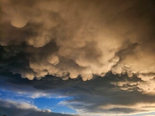 Storm clouds on sunset. Light in the dark and dramatic storm clouds. Background of storm clouds before a thunderstorm. Mammatus clouds