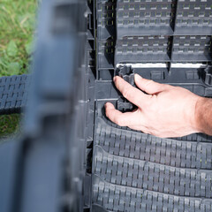 Assembling a plastic modular structure outdoors.  A hand connects components.