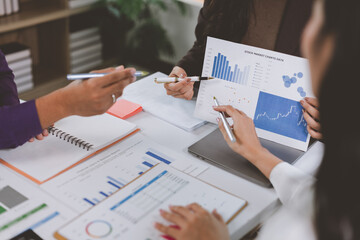 Businesswomen working together analyzing financial charts and graphs in office meeting