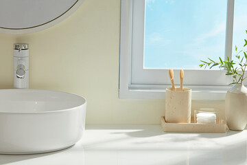 Modern Japandi bathroom with round sink, wooden brush holder, and delicate greens. Sunlight...