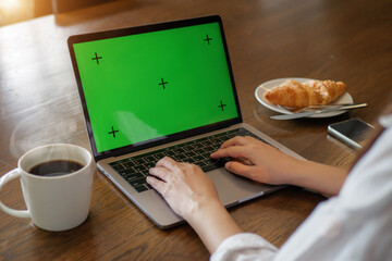 laptop blank green screen mockup. woman using laptop computer, hand typing on keyboard at home for...