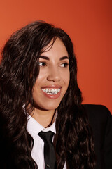 Young woman exudes confidence and charm in vibrant orange backdrop at student event