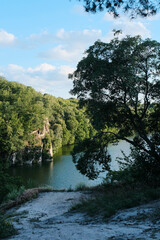 A serene river winds through a lush, forested canyon, offering a peaceful natural vista under a summer sky.