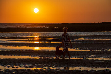 Mujer paseando por la playa durante la puesta de sol en Cadiz, España