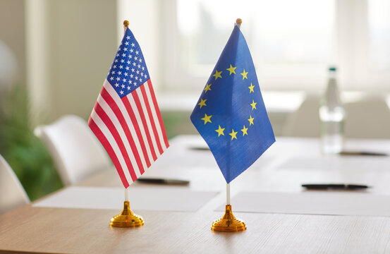 Flags of United States and European Union standing on meeting table. Symbol of diplomatic relations, international cooperation, political agreement or transatlantic partnership between NATO members.