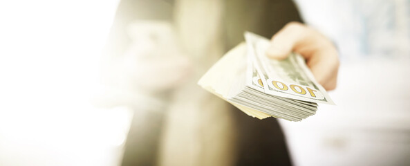 A bald man in a mask holds a stack of one hundred dollar bills. Payment of insurance and credit.