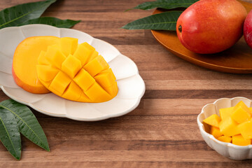 Fresh ripe mango with cubes on wooden table background.