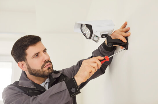 CCTV wall installation connecting bullet camera, worker setting up system for viewing and recording, motion detection home security, smart AI technology, night vision, mounting powering up and testing