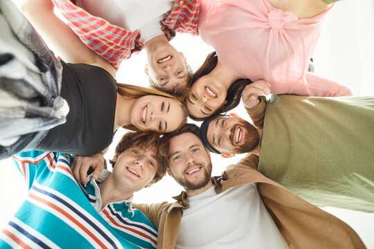 Group of friends, people standing together forming circle looking down brightly smiling happy, union feeling community cheerful and celebrating support, positive volunteering, helping team 