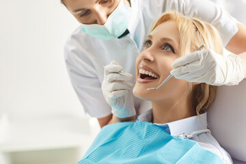 Professional woman stomatologist using dental tools for curing teeth of female patient. Woman...