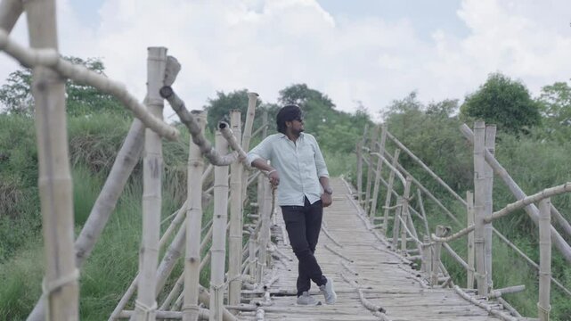 A man stands on the bamboo bridge built over the Damodar River and enjoys the natural beauty.