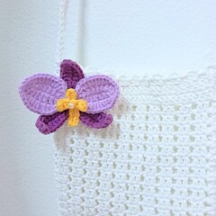 white crochet bag with purple orchid brooch