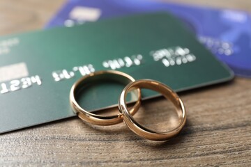 Gold wedding rings and credit cards on wooden table, closeup