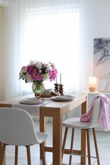 Beautiful table setting with bouquet of peonies in dining room. Interior design