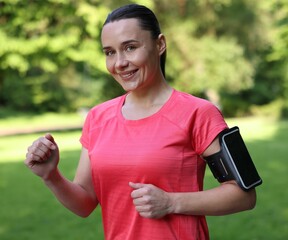 Sporty woman with armband running in park