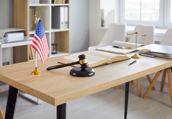 Closeup of modern office interior of judge or lawyer with wooden gavel and american flag on table....
