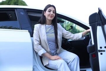 Woman getting out of modern car outdoors, low angle view