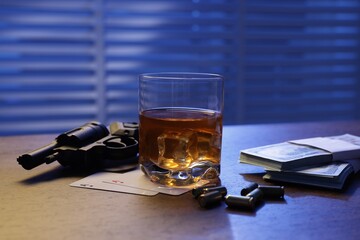Mafia and criminal world. Bullets, gun, whiskey, money and playing cards on wooden table indoors,...