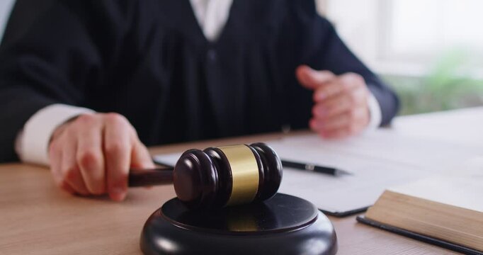 Close-up of judge using gavel or mallet in courtroom during government session, delivering verdict and judgment on law enforcement, focusing on sentence in a professional setting with authority.