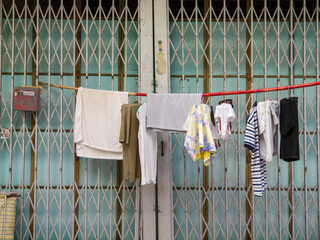 Drying clothes on a removable bamboo pole stick attached to a shutter grill door.