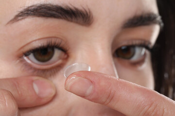 Beautiful woman putting in contact lens, closeup