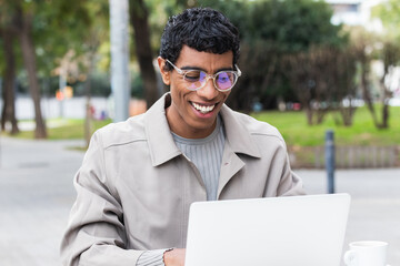 Smiling young indian man using laptop to work remotely, Portrait of successful freelancer or...