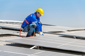 A solar panel installer wearing a hard hat and safety gear is shown installing solar panels on a...