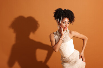 Fashionable portrait of beautiful Brazilian woman in stylish outfit on light brown background....