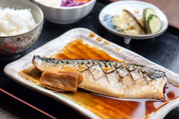 A plate of grilled mackerel with rice and pickled vegetables.