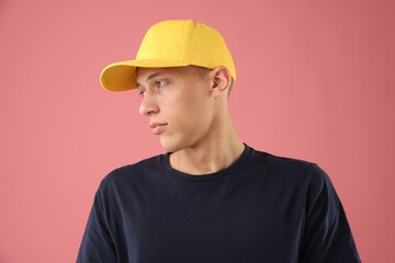 Young man in stylish baseball hat on pink background