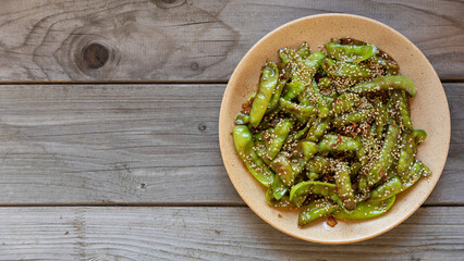 Asian Sugar Snap Peas. Pea pods stir-fried with garlic, ginger, and soy sauce, and sprinkled with toasted sesame seeds. Rustic wooden table with space for text.