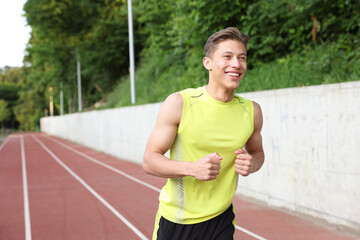 Sporty man running at stadium, space for text