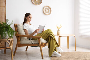 Beautiful woman reading book in comfortable armchair at home