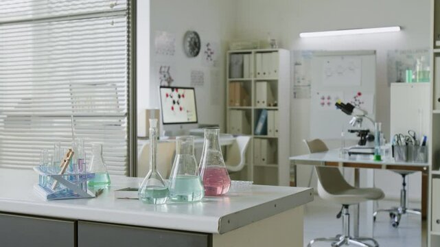 No people shot of computer displaying molecular structures, whiteboard with scientific notations, and microscope in clean, organized laboratory