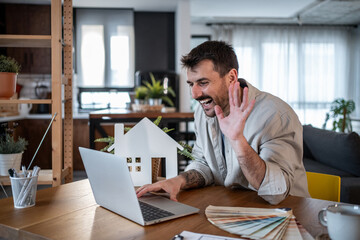 Architect waving during video call from home office