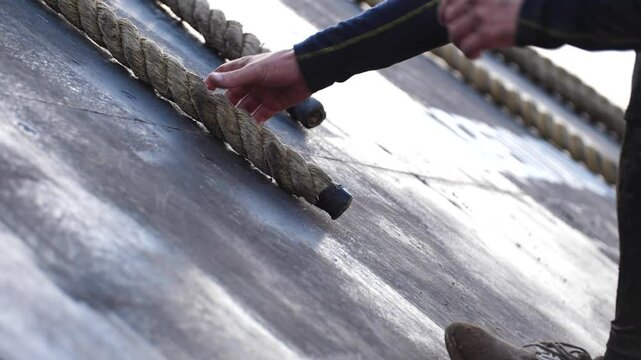 Slowed-down scene, two figures can be seen grasping ropes and making their way up onto a platform