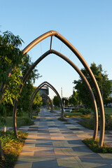 Symmetrical arched walkway with modern design and patterned tiles at sunset in an urban parkland