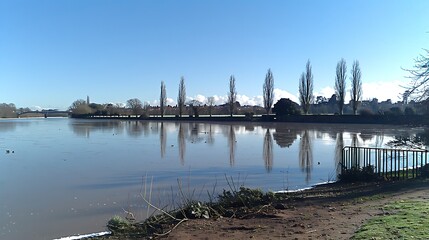 Picturesque lake scene showcasing reflections and bare trees under a clear sky offering scenic charm