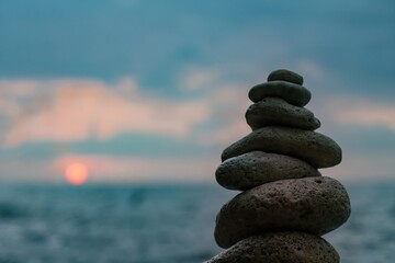 Stones Stacked Beach Sunset - A balanced pile of stones against a backdrop of a sunset over the ocean.